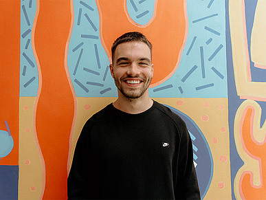 professional standing in front of a colourful wall and smiling