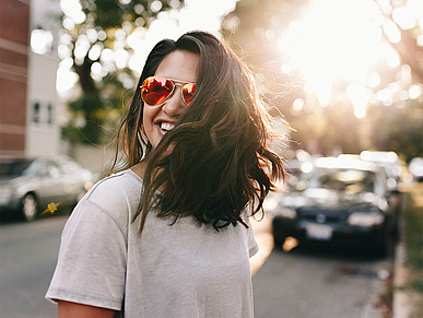 Lachende Pflegerin mit einer Sonnenbrille und brauen Haaren
